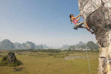 Female climber pulling up on overhanging rock in Yangshuo / China - CAVF89768