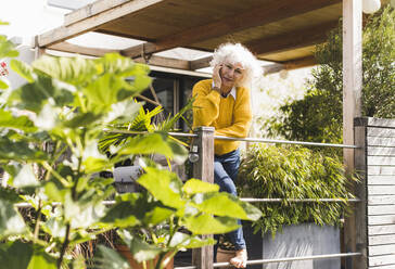 Mature woman with hand on chin standing in balcony at home - UUF21601