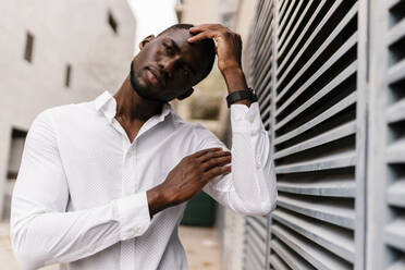 Thoughtful businessman looking away while leaning on fence in city - EGAF00837