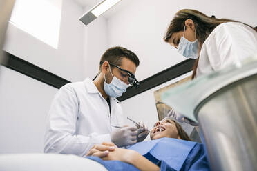 Arzt mit Hilfe einer Assistentin bei der Behandlung von Zahnkaries einer Patientin - ABZF03381