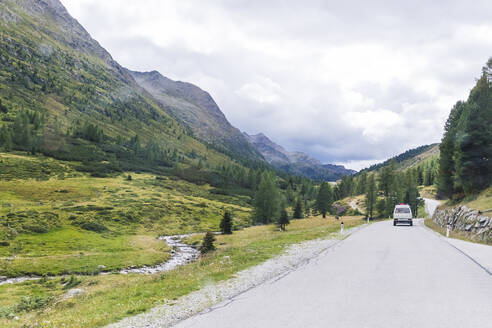 Auto auf der Straße in der Nähe der Bergkette gegen den bewölkten Himmel an einem sonnigen Tag, Sextner Dolomiten, Dolomiten, Südtirol, Italien - MMAF01397