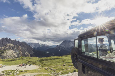 Weibliche Touristin, die die berühmten Dolomiten betrachtet, während sie mit dem Auto gegen den Himmel bei Sonnenuntergang steht, Sextner Dolomiten, Südtirol, Italien - MMAF01398