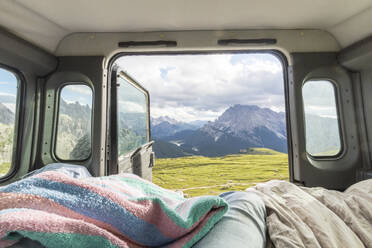 Male tourist relaxing in campervan against mountain range, Sesto Dolomites, Dolomites, Alto Adige, Italy - MMAF01399