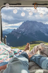 Mann entspannt sich im Wohnmobil vor einer Bergkette, Sextner Dolomiten, Dolomiten, Südtirol, Italien - MMAF01400
