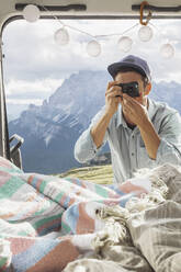 Männlicher Tourist fotografiert das Innere eines Wohnmobils vor dem Hintergrund der Berge, Sextner Dolomiten, Dolomiten, Südtirol, Italien - MMAF01402