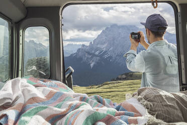 Man photographing scenic mountain ranges while standing by campervan. Sesto Dolomites, Dolomites, Alto Adige, Italy - MMAF01403