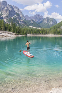 Man paddleboarding on turquoise Pragser Wildsee, Dolomites, Alto Adige, Italy - MMAF01420