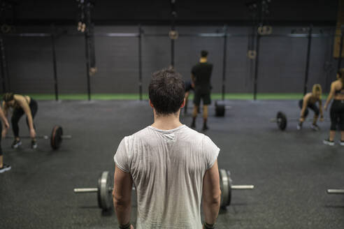 Man standing with athletes exercising in background in gym - SNF00555