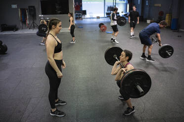 Athlete helping each other while exercising in gym - SNF00556