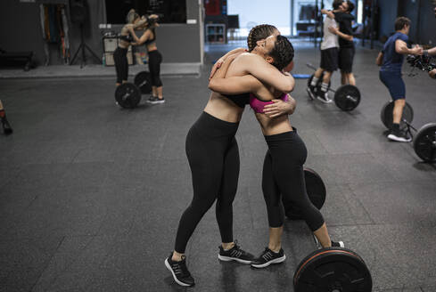 Athletes hugging each other while standing at gym - SNF00558