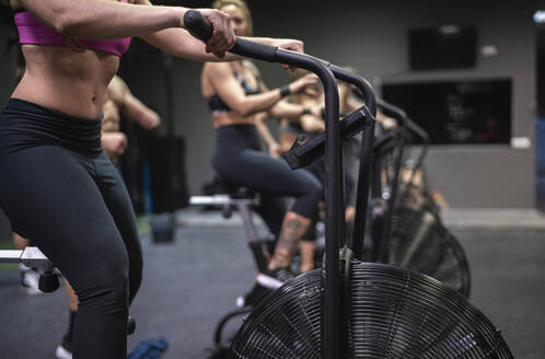 Athletes exercising on fitness bike in gym - SNF00568