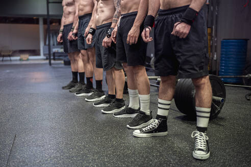 Shirtless athlete wearing sports shoe and shorts standing at gym - SNF00578