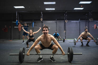 Athleten, die eine Langhantel beim Training im Fitnessstudio in die Hand nehmen - SNF00590