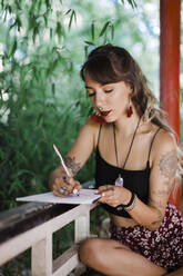 Schöne Frau schreibt ein Buch und sitzt auf einer Bank - DCRF00906