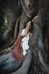 Woman lying on tree trunk at park - DCRF00922