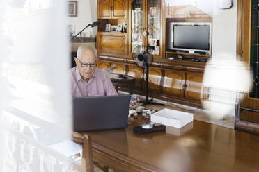 Elderly man using laptop at table - JRFF04769