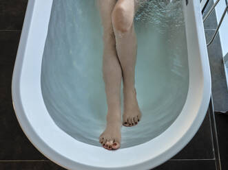 Ältere Frau nimmt ein Bad in einer Badewanne in einem Luxushotelzimmer - ZEDF03884