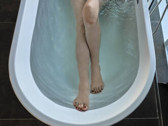 Senior woman taking bath in bathtub at luxury hotel room - ZEDF03884