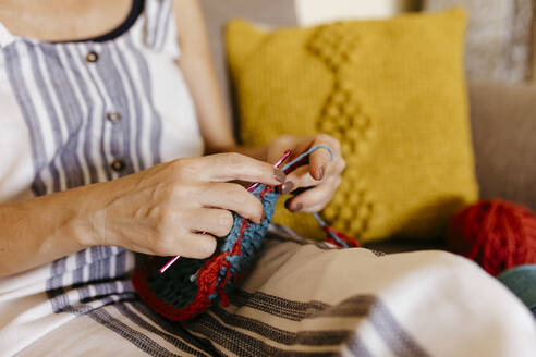 Reife Frau strickt, während sie zu Hause auf dem Sofa sitzt - TCEF01193