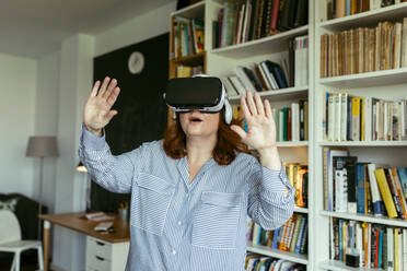 Woman using virtual reality glasses while standing at home - VABF03569