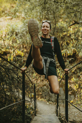 Smiling woman swinging on bridge railing at Sierra De Hornachuelos, Cordoba, Spain stock photo