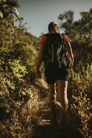 Woman with backpack trekking on path of mountain at Sierra De Hornachuelos, Cordoba, Spain stock photo