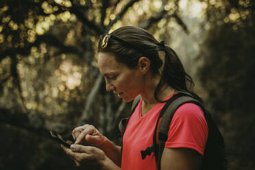 Wanderer, der ein Mobiltelefon benutzt, während er in der Sierra De Hornachuelos, Cordoba, Spanien steht - DMGF00178