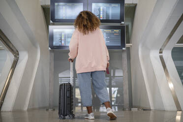 Junge Frau prüft Flugplan auf Zeittafel am Flughafen - SNF00598