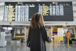 Junge Frau, die die Ankunftszeit eines Fluges an Bord überprüft, steht am Flughafen - SNF00605