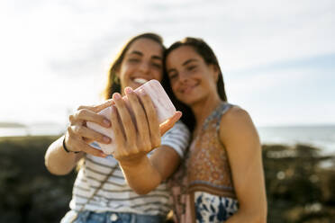 Glückliche junge Schwestern nehmen Selfie durch Smartphone am Strand während des Wochenendes - MGOF04482