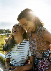 Cheerful young female friends enjoying weekend together on sunny day - MGOF04499