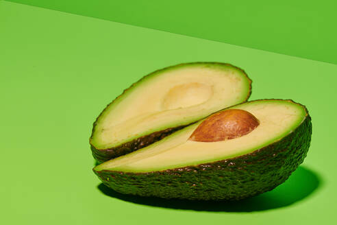 Frische grüne natürliche Avocado in zwei Hälften geschnitten mit Samen auf hellgrünem Hintergrund platziert - ADSF16193