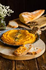 Appetitlicher Hummus mit Süßkartoffeln auf einem Holztisch mit Brot in der Küche zum Mittagessen - ADSF16201