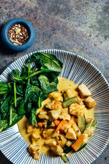 Delicious Thai Curry Coconut Chicken, accompanied by tender vegetables and spinach, in a modern blue plate - ADSF16268