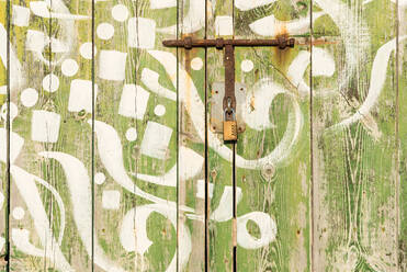 Old colorful wooden door with paintings and metal bolts lit by sunlight in Sa Caleta - ADSF16302