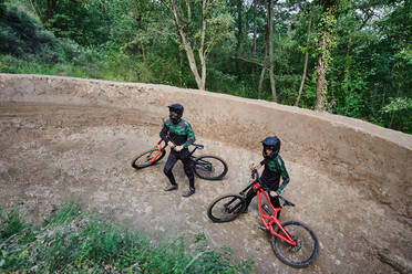 From above unrecognizable male bikers with bicycles for downhill standing in woods - ADSF16360