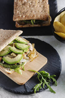 Leckeres Sandwich mit Avocado auf dem Tisch mit einem Glas Bier und Kartoffelchips im Café - ADSF16410