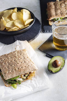 Draufsicht auf ein frisch zubereitetes Avocado-Sandwich mit Gemüseschnitzel, das zum Mittagessen auf dem Tisch im Café liegt - ADSF16412