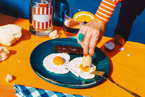 Arm of woman eating fried eggs with chorizo - ERRF04548