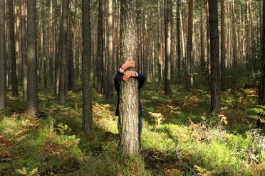 Reife Frau mit umarmendem Baumstamm im Wald im Herbst - JTF01658