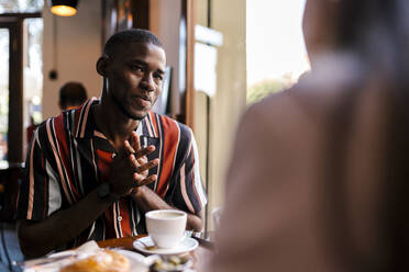 Smiling young man with girlfriend in coffee shop - EGAF00889