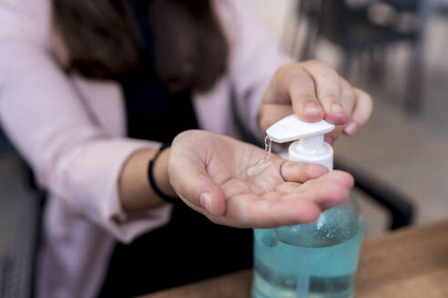 Businesswoman using hand sanitizer in cafe during coronavirus outbreak - EGAF00903