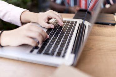 Businesswoman using laptop at table in coffee shop - EGAF00911