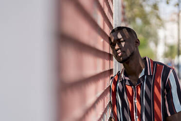 Young man in casuals leaning on fence outdoors - EGAF00931