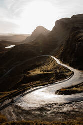 Spektakuläre Landschaft mit Bergen und kurvenreicher Straße bei bewölktem Himmel und strahlender Sonne am Morgen in den schottischen Highlands - ADSF16478