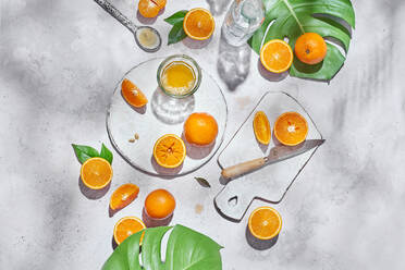 Top view of whole and half of ripe oranges arranged on table with knife and glass with juice - ADSF16525