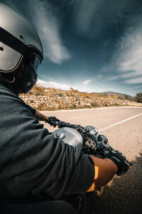 Rückenansicht abgeschnitten unerkennbar männlichen Fahrer in Lederjacke und Helm fahren Motorrad auf der Straße gegen bewölkten Himmel in der Landschaft - ADSF16559