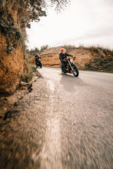 Unbekannte Motorradfahrer in einer Kurve einer schmalen Asphaltstraße, die durch bergiges Gelände führt - ADSF16564