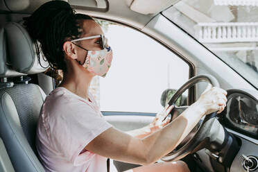 Frau mit Schutzmaske beim Autofahren in der Stadt an einem sonnigen Tag - EBBF00790