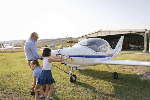 Kinder und Großvater ziehen das Flugzeug aus dem Hangar - EIF00202